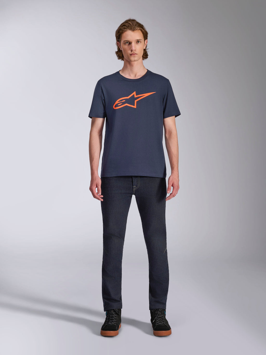 Alpinestars Ageless 2.0 CSF Tee, Short Sleeve T-Shirt, Navy Blue with Orange Alpinestars Logo, worn by model with dark jeans and sneakers, Casual Motorsport Streetwear
