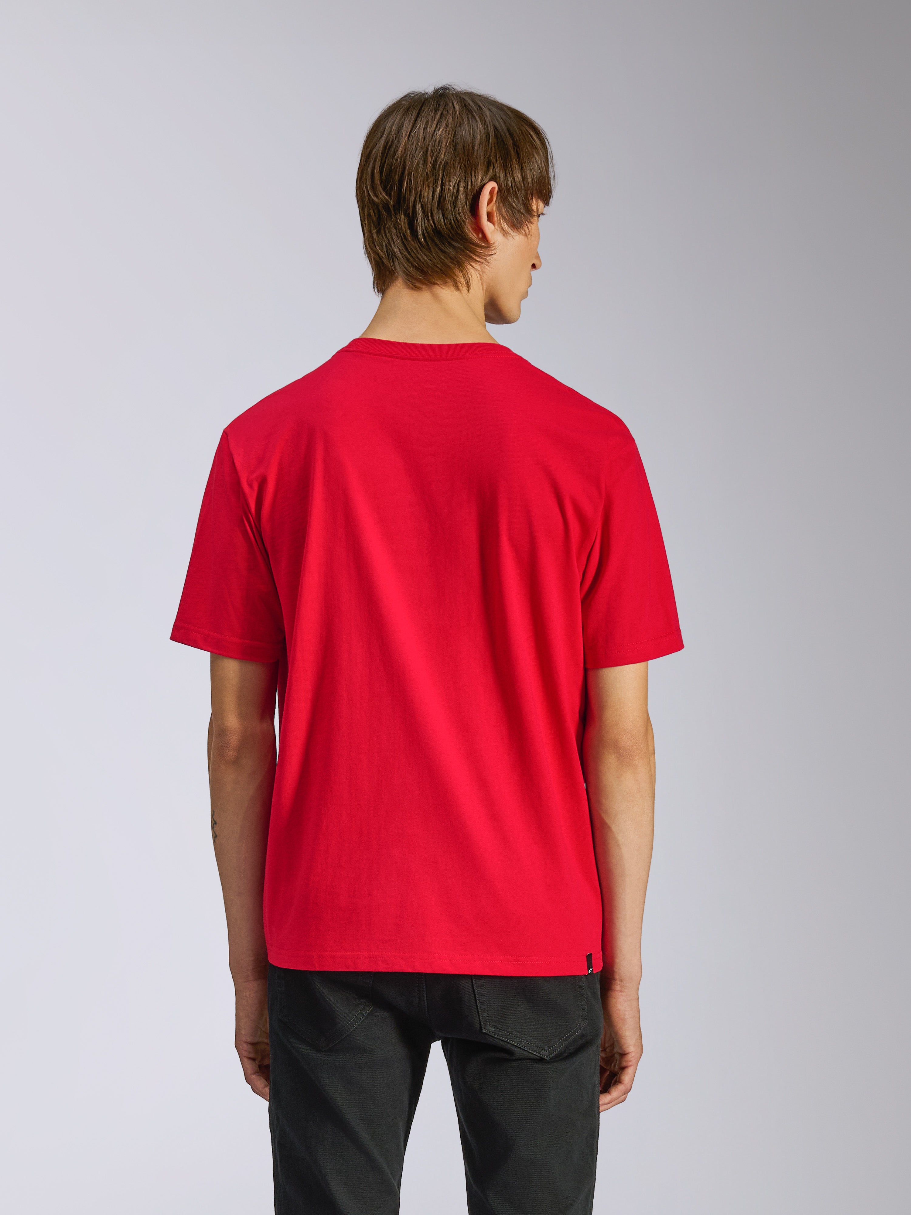 Alpinestars Ageless Shadow CSF Tee, Kurzarm-T-Shirt, Rot, Rückansicht am Modell, kombiniert mit schwarzer Hose, lässige Motorsport-Streetwear