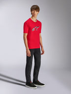 Alpinestars Ageless Shadow CSF Tee, rotes Kurzarm-T-Shirt, mit großem Ageless-Logo auf der Brust, getragen von einem Model mit schwarzer Hose und Sneakern, lässige Motorsport-Streetwear