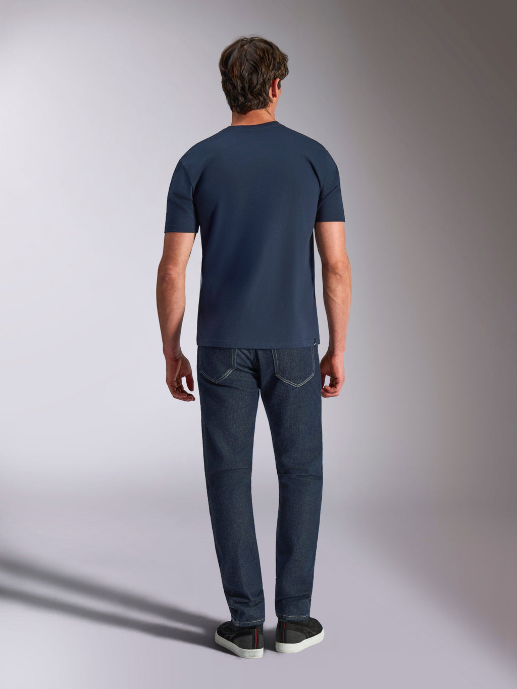 Alpinestars Ageless Shadow CSF Tee, Kurzarm-T-Shirt, Navy, Rückansicht eines Models mit dunkler Jeans und schwarzen Sneakern, lässige Motorsport-Streetwear.