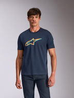 Alpinestars Ageless Shadow CSF Tee, Kurzarm-T-Shirt, Marineblau mit orangefarbener und hellblauer Schattenlogo-Grafik, getragen von einem Model mit dunkler Jeans, lässige Motorsport-Streetwear