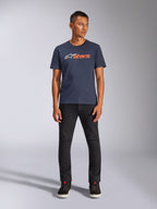 Alpinestars Blaze 2.0 CSF Tee, kurzärmeliges T-Shirt, Marineblau mit weißem und orangefarbenem Astars-Logo, getragen mit schwarzer Hose und schwarzen Sneakern, lässige, vom Motorsport inspirierte Streetwear