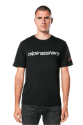Alpinestars Linear Wordmark 2.0 CSF Tee, kurzärmeliges T-Shirt, Schwarz, graue Linear-Wortmarke auf der Brust und rotes Ageless-Logo am Ärmel, getragen von einem Model mit dunkler Jeans, lässige vom Motorsport inspirierte Streetwear