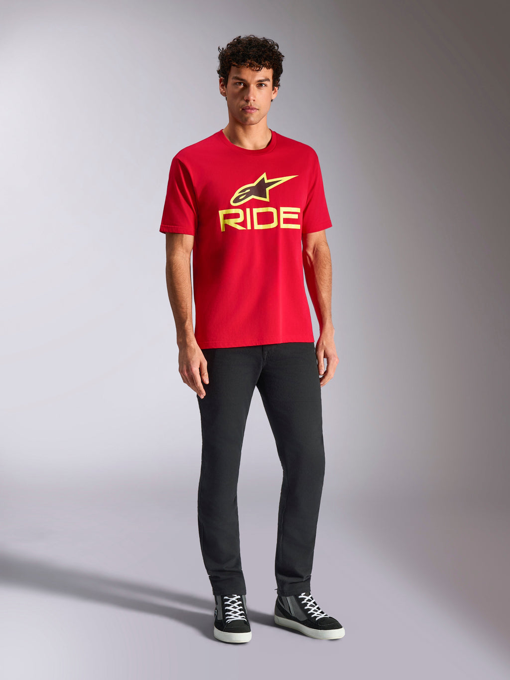 Alpinestars Ride 4.0 CSF Tee, Kurzarm-T-Shirt, Rot mit neongelbem Alpinestars Stern- und Ride-Logo, getragen von einem Model mit schwarzer Hose und Sneakern, lässige Motorsport-Sportbekleidung
