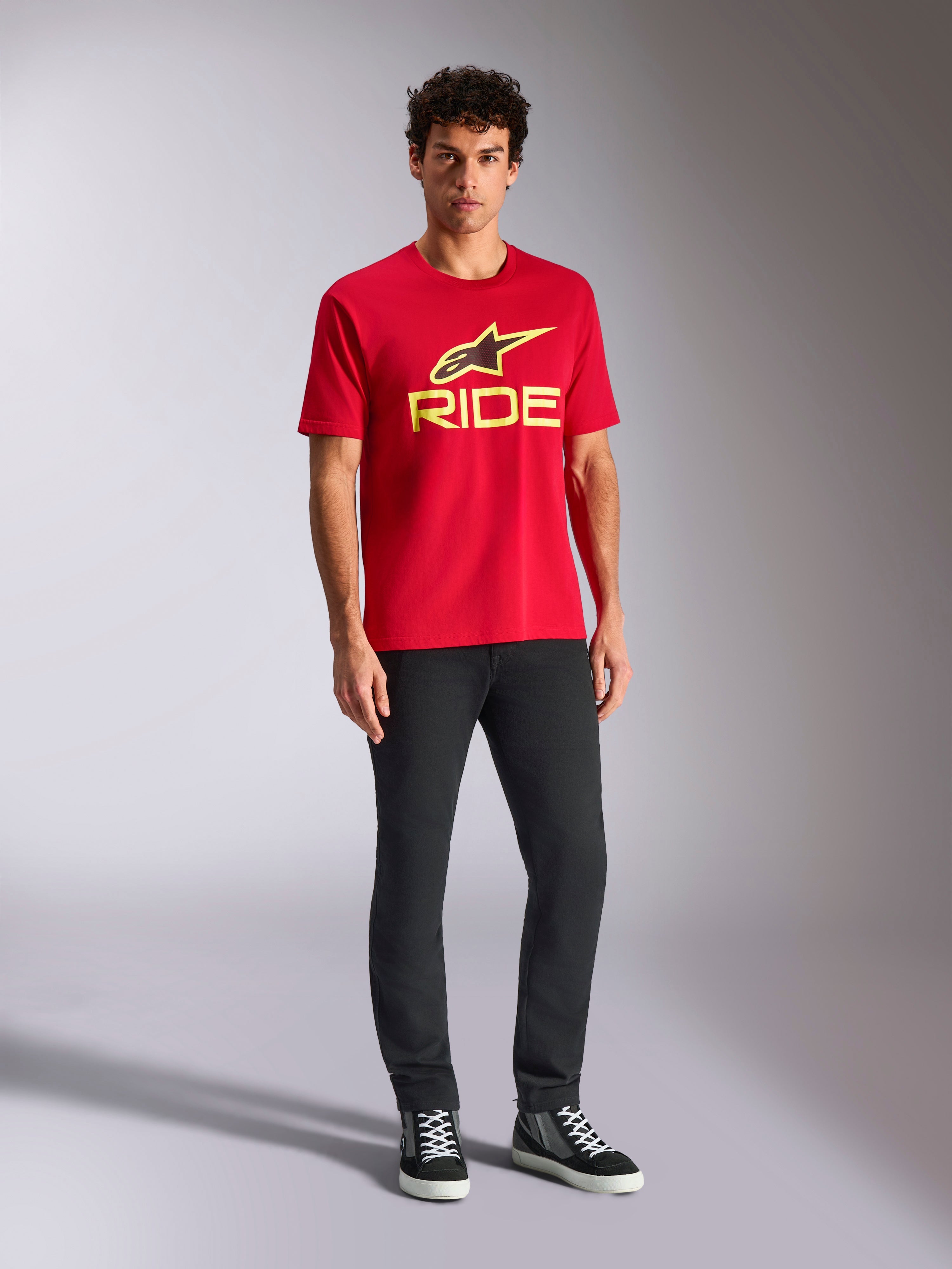 Alpinestars Ride 4.0 CSF Tee, Kurzarm-T-Shirt, Rot mit neongelbem Alpinestars Stern- und Ride-Logo, getragen von einem Model mit schwarzer Hose und Sneakern, lässige Motorsport-Sportbekleidung