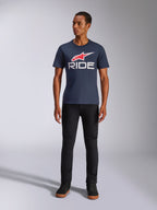Alpinestars Ride 4.0 CSF Tee, kurzärmeliges T-Shirt, Marineblau mit rotem Alpinestars Stern-Logo und weißem 'RIDE'-Schriftzug auf der Brust, getragen von einem Model mit schwarzer Hose und schwarzen Sneakern, lässige, vom Motorsport inspirierte Streetwear