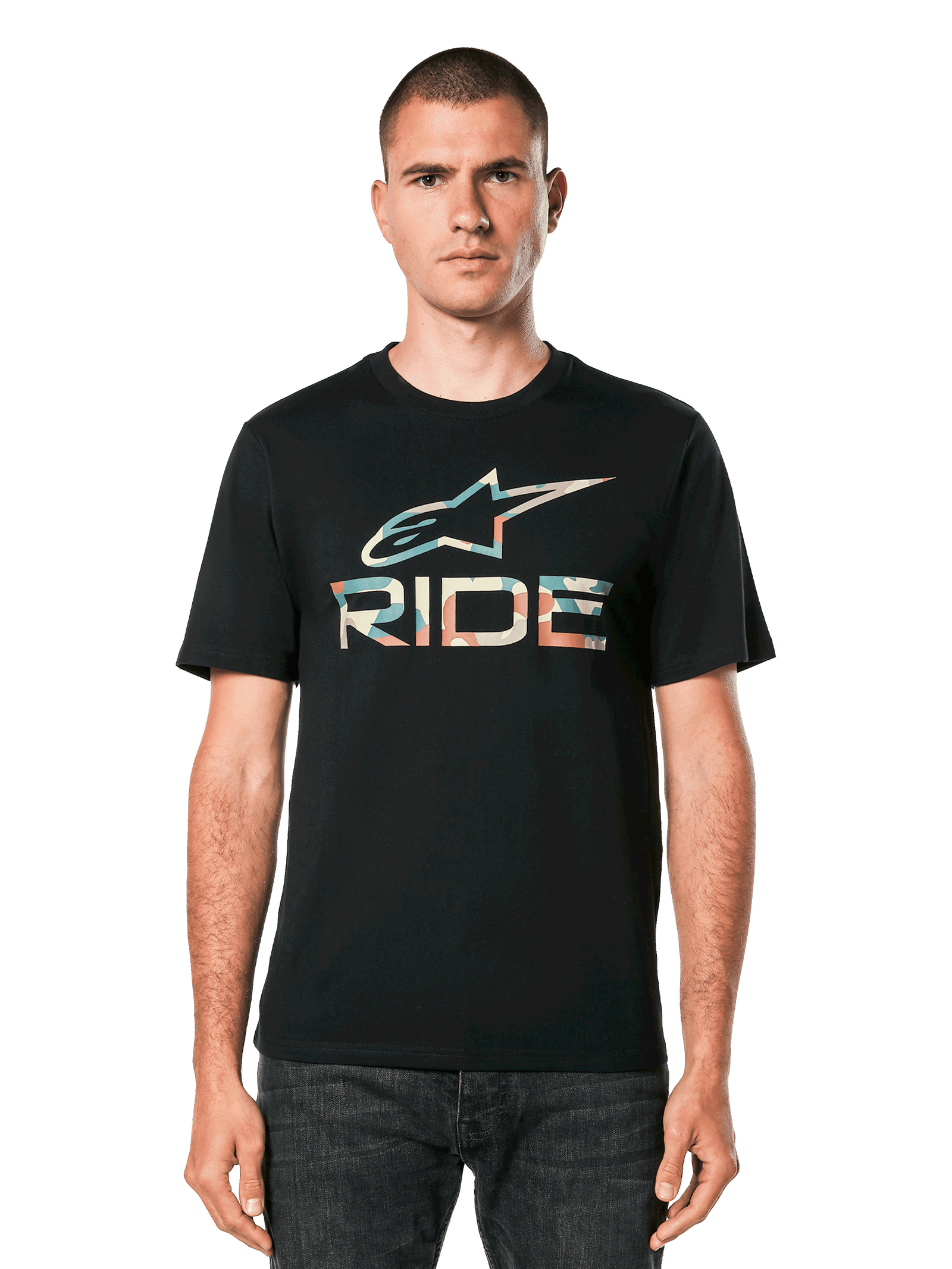 A person stands facing forward, wearing the Alpinestars Ride 4.0 Camo CSF Tee. The black T-shirt features a soft hand print with a colorful graphic logo and the word "RIDE" beneath. The person has short hair and a neutral expression. The background is plain black.