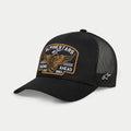 Alpinestars Heritage Patch Trucker Mütze, Schwarz, strukturierte Krone mit gebogenem Schirm, großer bestickter Heritage-Patch vorne mit geflügeltem Rad und 'Racing Ahead Est. 1963', schwarze Mesh-Rückseite mit seitlichem Stern-Logo, lässige Motorsport-Lifestyle-Kopfbedeckung