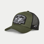 Alpinestars Heritage Patch Trucker Mütze, Military Black und Olivgrün, gebogener Schirm mit strukturierter Krone, großer bestickter Front-Patch mit Vintage-Motorradrad-Grafik und „Racing Ahead“-Schriftzug, schwarze Mesh-Rückseite mit weißem Ageless-Logo an der Seite.