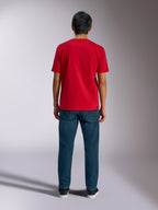 Alpinestars Ageless Shadow CSF T-Shirt, Rückansicht eines roten Kurzarm-T-Shirts, kombiniert mit dunkelblauen Denim-Jeans und schwarzen Sneakern, lässige Motorsport-Streetwear