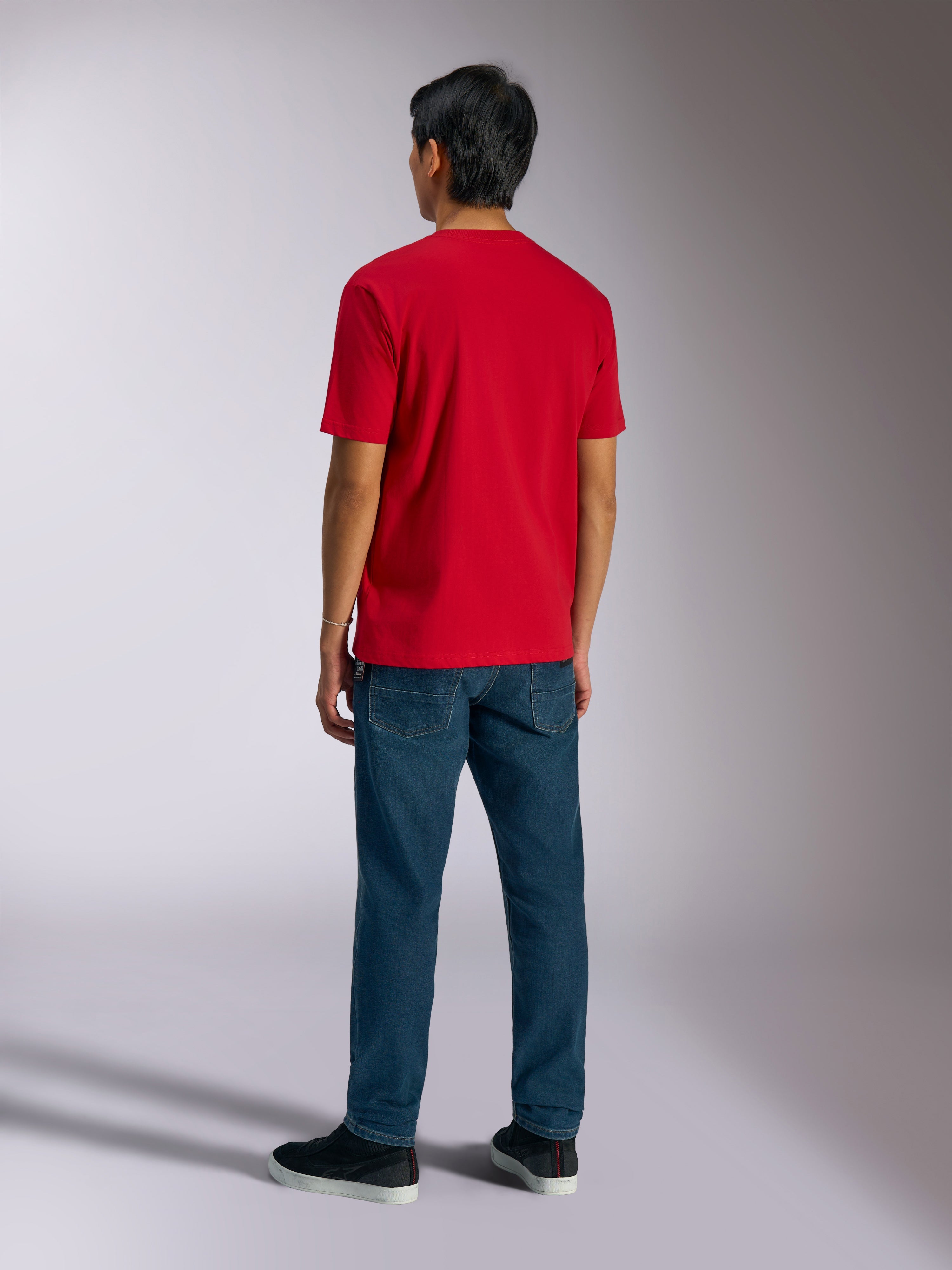Alpinestars Ageless Shadow CSF Tee, Kurzarm-T-Shirt, Rot, Rückansicht getragen von einem Modell mit blauen Jeans und schwarzen Sneakern, lässige Motorsport-Streetwear