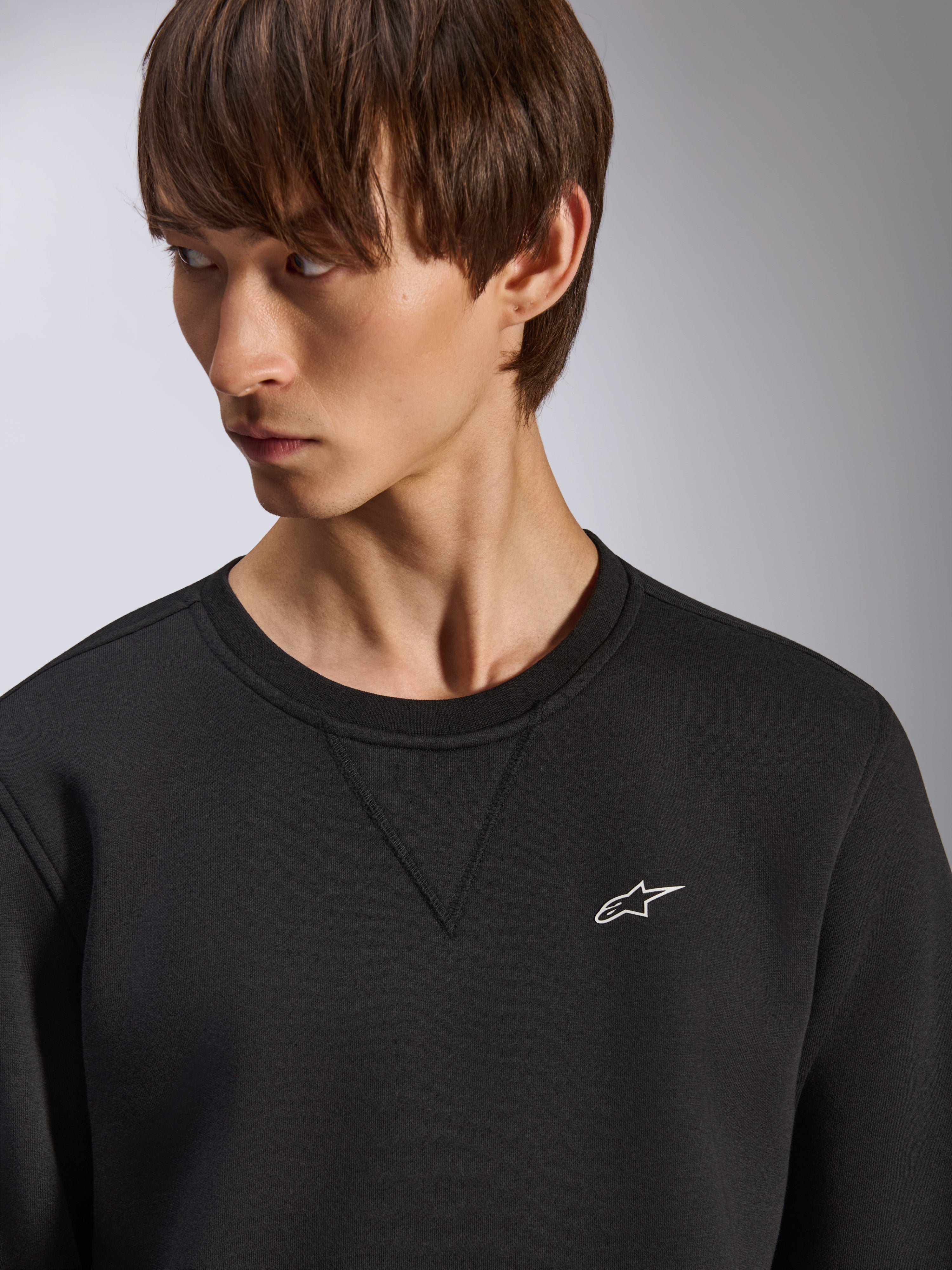Alpinestars Positive Crew Sweatshirt, schwarzer Rundhalsausschnitt mit V-Naht-Detail am Kragen, kleines weißes Alpinestars-Logo auf der linken Brust, lässige motorsport-inspirierte Streetwear