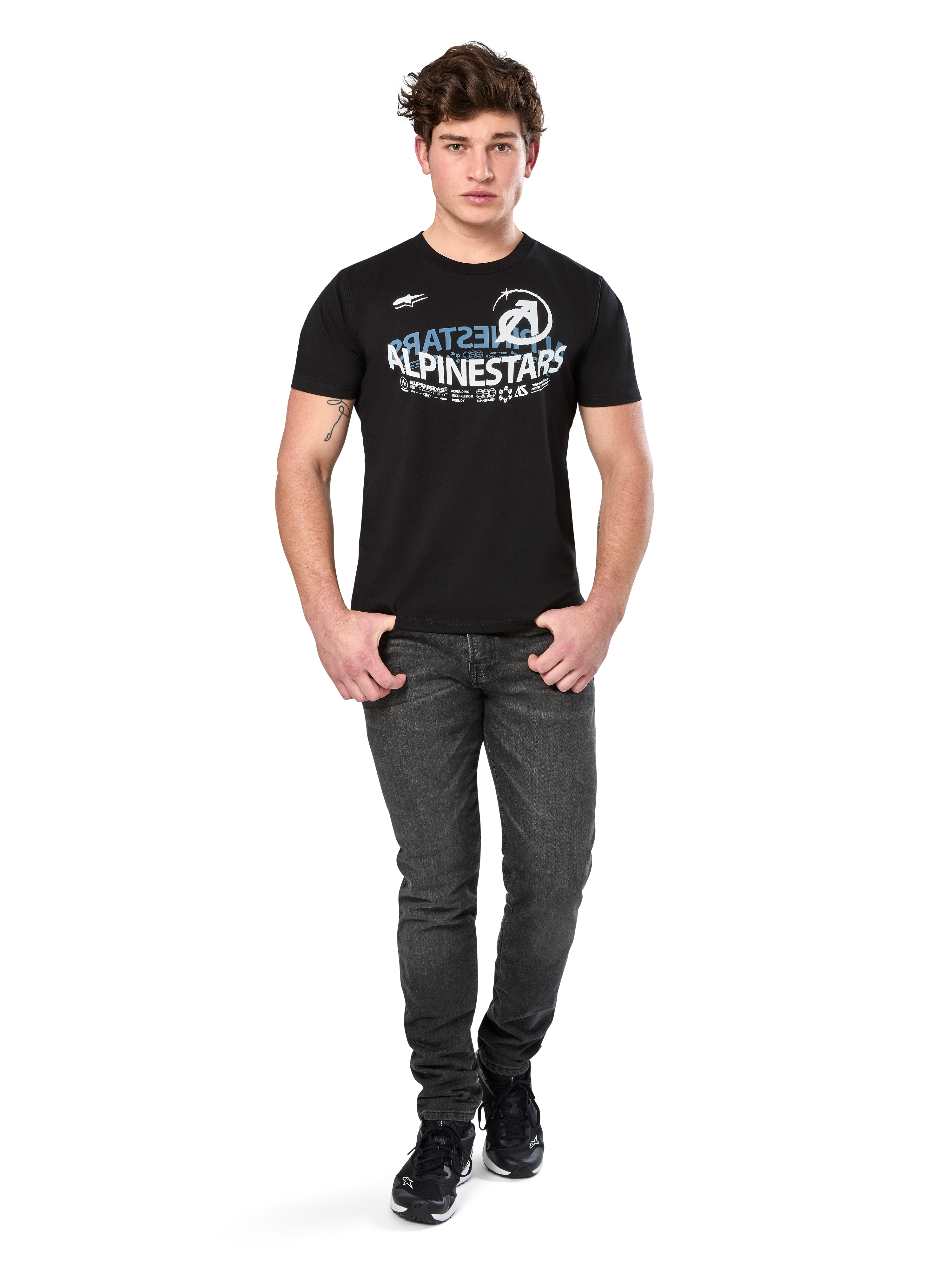 Alpinestars Semicircle CSF Tee, Kurzarm-T-Shirt, Schwarz, weißes und hellblaues geschwungenes Grafik-Design auf der Brust, getragen von einem Modell mit dunkelgrauen Jeans und schwarzen Sneakern, lässige Motorsport-Streetwear