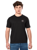 Alpinestars Dot Carbon CSF Tee, Kurzarm-T-Shirt, Schwarz, kleines rundes Brustlogo mit weißem Astar und roter Umrandung, von einem Model mit blauen Jeans getragen, lässige Motorsport-Streetwear