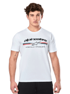 Alpinestars Prevail CSF Tee, weißes Kurzarm-T-Shirt, mit dreifarbigem Streifenlogo im Paddock-Stil, roten und blauen Akzenten, schwarzem Alpinestars-Branding und „Premium Racewear“-Schriftzug, getragen von einem männlichen Model, lässige Motorsport-Bekleidung