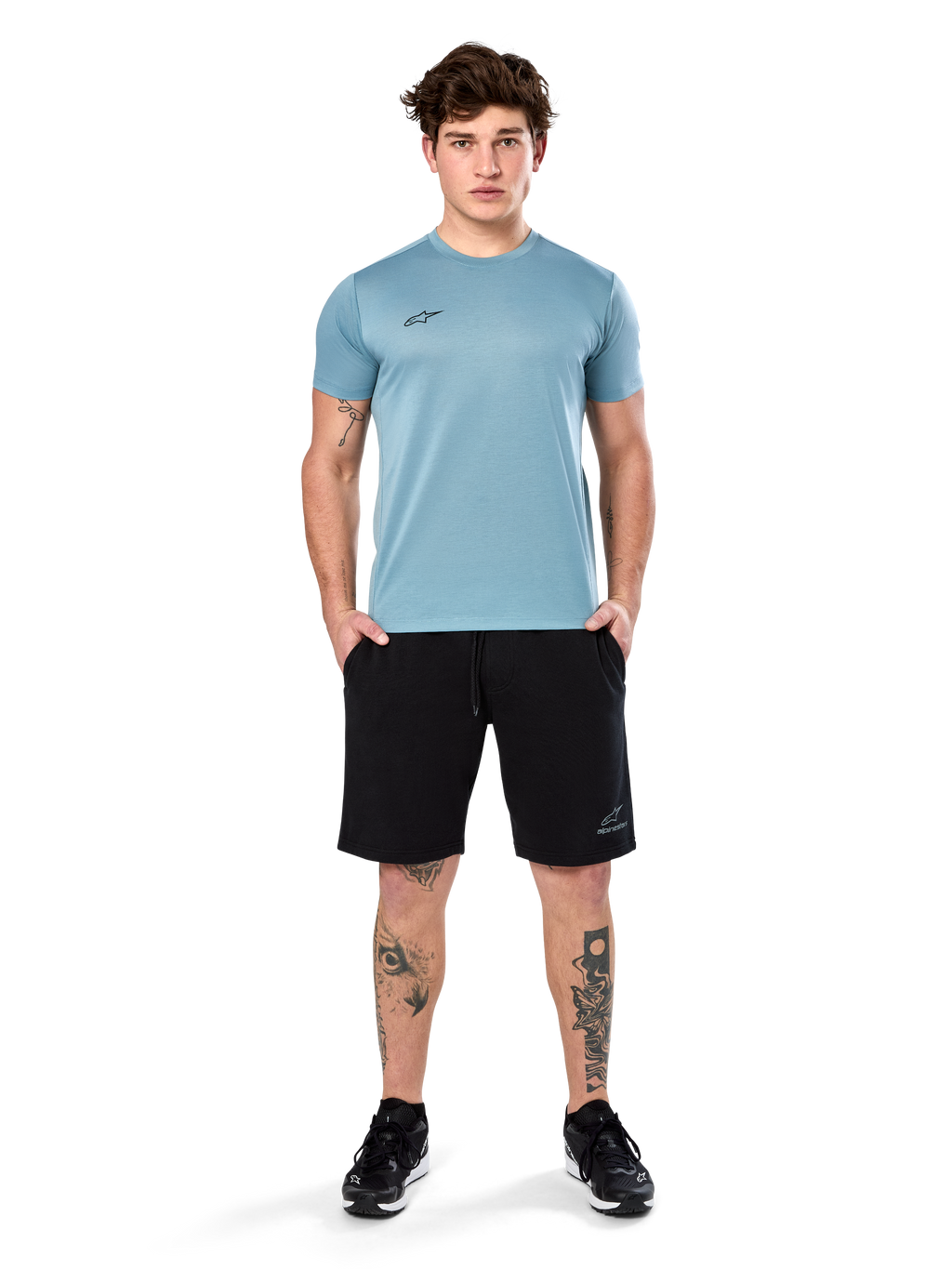 Alpinestars Point Performance Tee, Kurzarm-T-Shirt, Ice Blue, mit kleinem schwarzen Logo vorne, Rundhalsausschnitt, getragen von einem Model mit schwarzen Shorts und schwarzen Sneakern, lässige feuchtigkeitsableitende Sportbekleidung