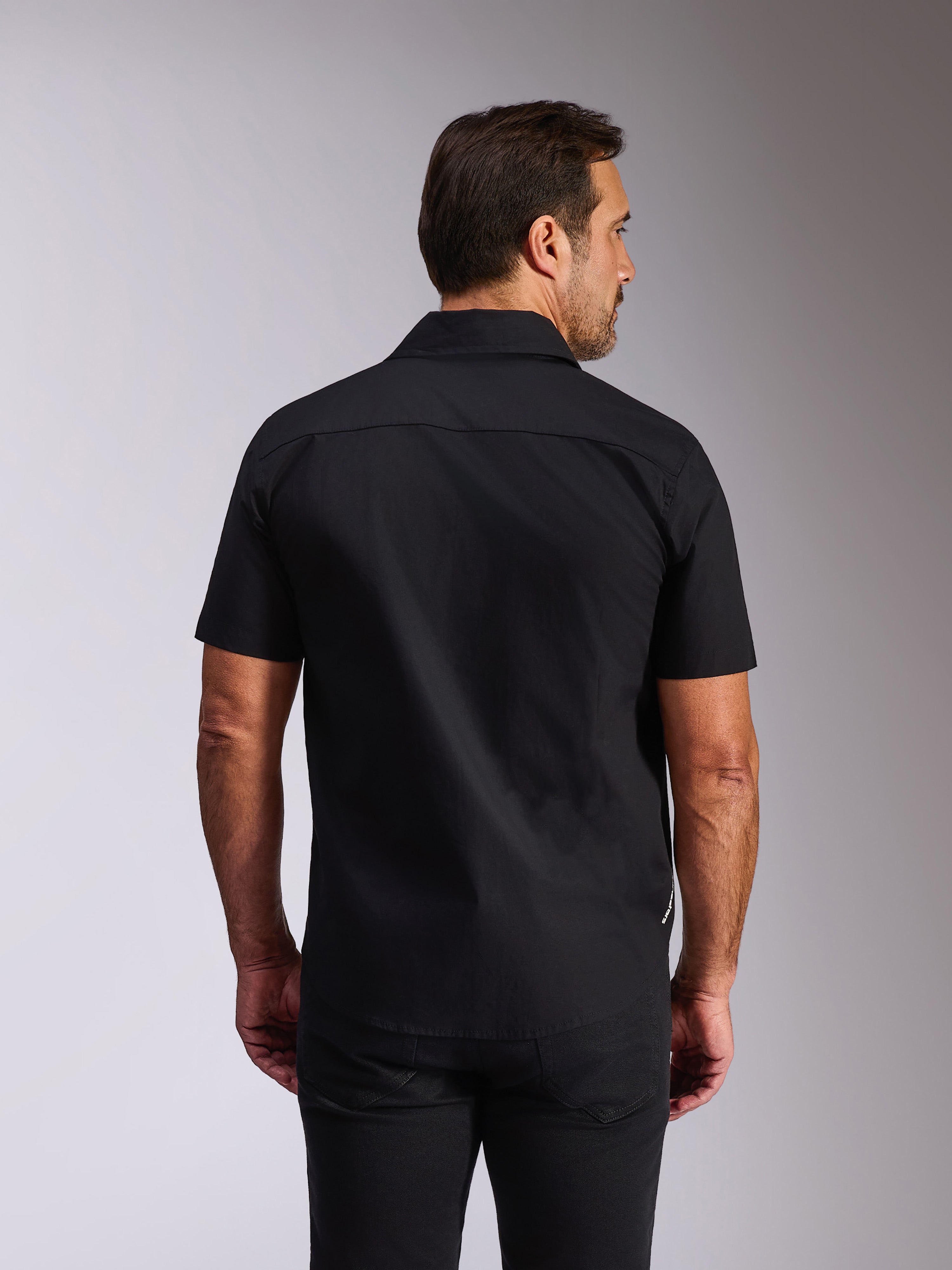 Alpinestars Strive Woven Hemd, schwarzes Kurzarmhemd mit Knopfleiste, Rückansicht zeigt Rückenpasse und taillierte Passform, lässige vom Motorsport inspirierte Streetwear
