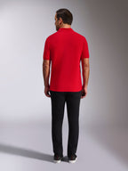 Alpinestars Endeavor Classic Polo, rotes Piqué-Poloshirt, Rückansicht, kombiniert mit einer schwarzen Hose, lässige Motorsport-Streetwear mit Rippkragen und Ärmelbündchen