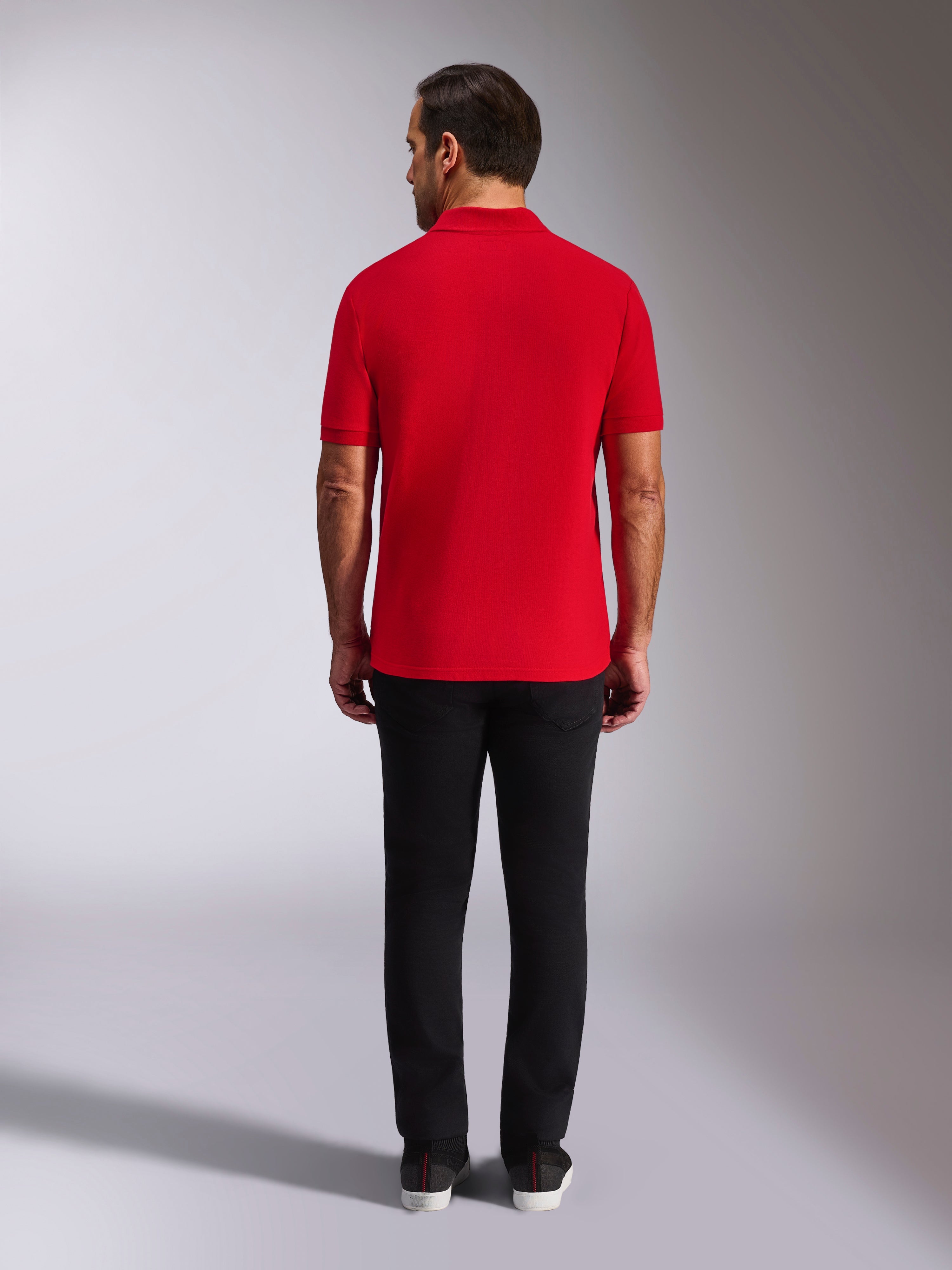 Alpinestars Endeavor Classic Polo, rotes Piqué-Poloshirt, Rückansicht, kombiniert mit einer schwarzen Hose, lässige Motorsport-Streetwear mit Rippkragen und Ärmelbündchen
