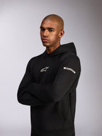 Alpinestars Insight Hoodie, lässiger Sportswear-Kapuzenpullover, Schwarz, weißes Astars-Logo auf der Brust und Wortlogo am Oberärmel, Model trägt Kapuzenpullover mit verschränkten Armen, hochwertige Doppelvlies-Konstruktion