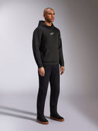 Alpinestars Insight Hoodie, Schwarz, lässiger Fleece-Kapuzenpullover mit weißem Astars-Logo auf der Brust, Kängurutasche, getragen mit schwarzer Hose und Sneakern, Ganzkörper-Studioaufnahme, motorsport-inspirierte Streetwear