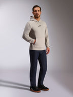 Alpinestars Insight Kapuzenpullover, lässige Streetwear, Zementgrau mit schwarzem Astars-Logo auf der Brust, Pullover-Design mit Kängurutasche, getragen mit dunkelblauer Jeans und schwarzen Sneakern, moderner, vom Motorsport inspirierter Stil