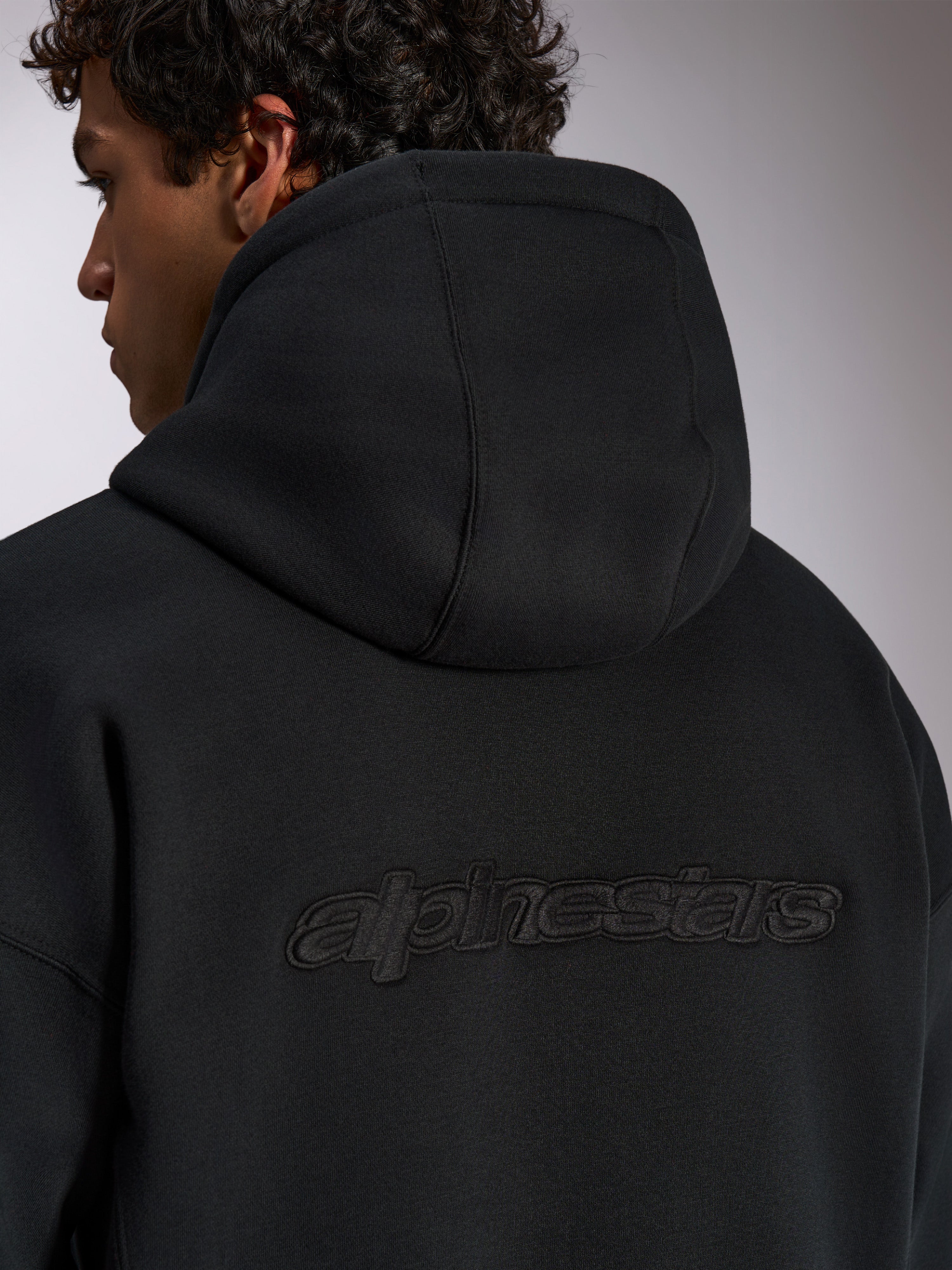 Alpinestars Emergent Oversized Kapuzenpullover, schwarze lässige Streetwear, Rückansicht mit 3D-besticktem Alpinestars-Wortlogo, Oversized-Passform mit hochwertiger Fleece-Textur