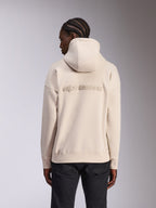 Alpinestars Emergent Oversized Hoodie, lässige Streetwear, Farbe Sand-Off-White, mit 3D-besticktem Alpinestars-Wortlogo auf dem Rücken, Oversized-Passform mit Rippbündchen an Saum und Ärmeln, Rückansicht am Modell mit schwarzer Hose.
