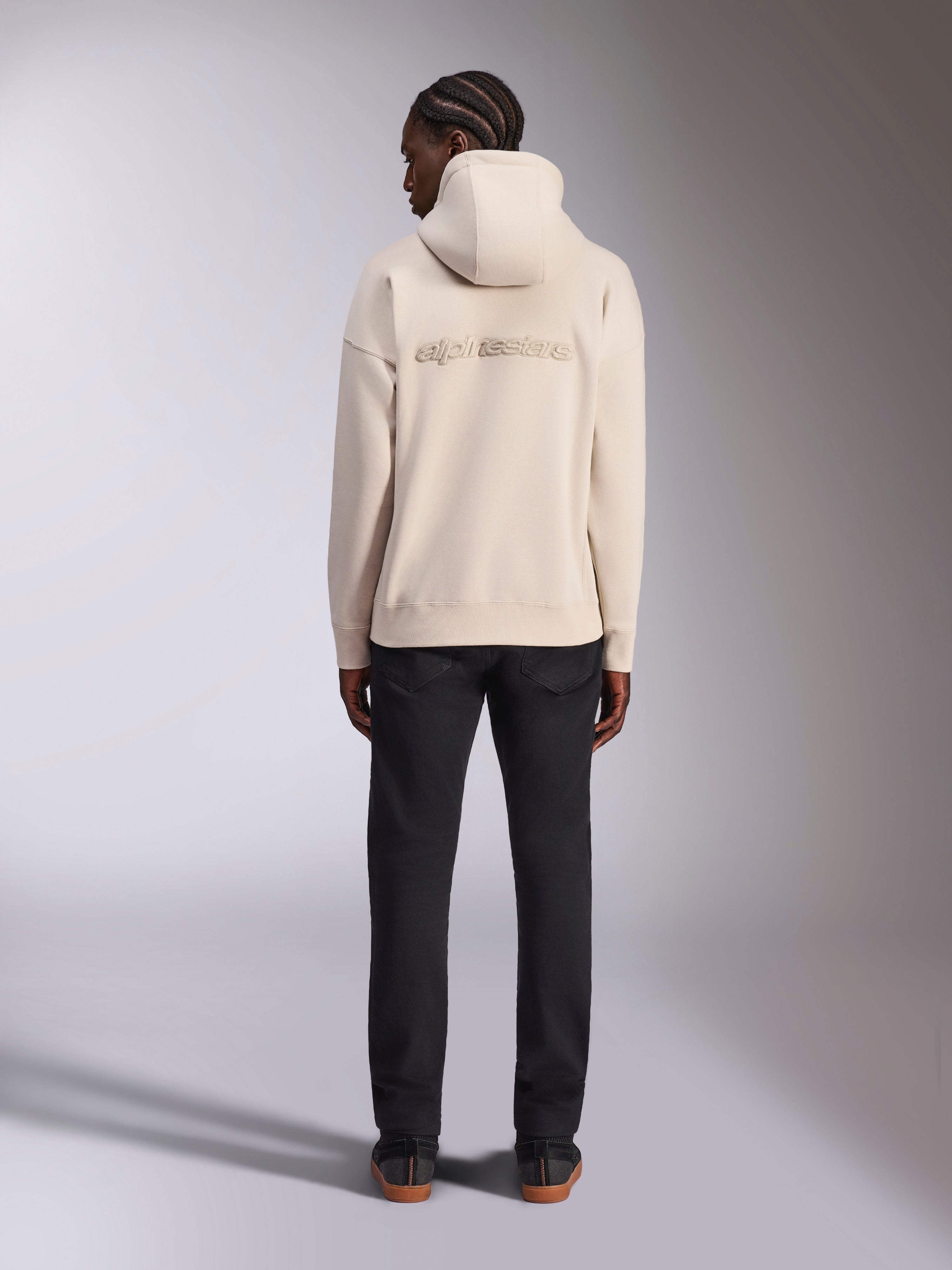 Alpinestars Emergent Oversized Hoodie, Off White, Rückansicht mit 3D-gesticktem Alpinestars-Wortlogo, Fleece-Pullover in Oversized-Passform, kombiniert mit schwarzer Hose, lässiges Streetwear-Design