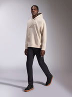 Alpinestars Emergent Oversized Hoodie, lässige Streetwear, Sand-Off-White, tonale 3D-Logo-Stickerei, getragen von einem Model mit schwarzer Hose und schwarzen Sneakern, entspannte Oversized-Passform mit Kängurutasche und Kapuze mit Kordelzug