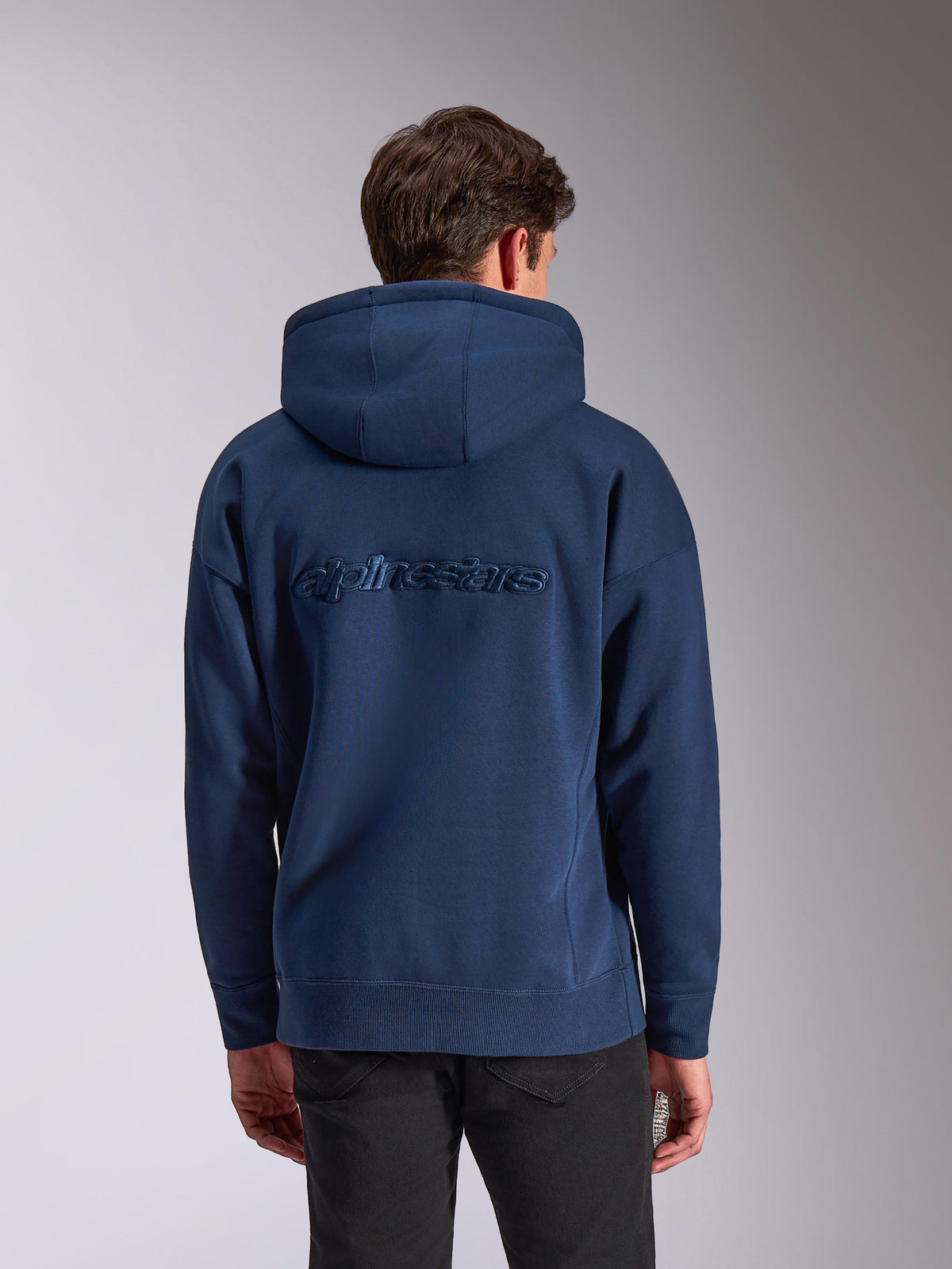 Alpinestars Emergent Oversized Hoodie, Marineblau, Rückansicht mit Ton-in-Ton besticktem Alpinestars-Wortlogo, lässiger Fleece-Hoodie, Oversized-Passform, Kapuze mit Kordelzug und Rippbündchen, Motorsport-inspirierte Streetwear.