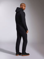 Alpinestars Ellipsoid Hoodie, schwarze Freizeit-Streetwear, Rückansicht an einem männlichen Model, Fleece-Kapuzenpullover mit Rippbündchen und Saum, getragen mit schwarzer Hose und Sneakern, modernes, vom Motorsport inspiriertes Design