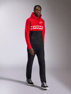 Alpinestars Parallel Hoodie, lässige Sportbekleidung, rot-schwarzes Color-Block-Design, weißer Alpinestars-Schriftzug und Stern-Logo auf der Brust, kombiniert mit schwarzer Hose und Sneakern, moderner, vom Motorsport inspirierter Look