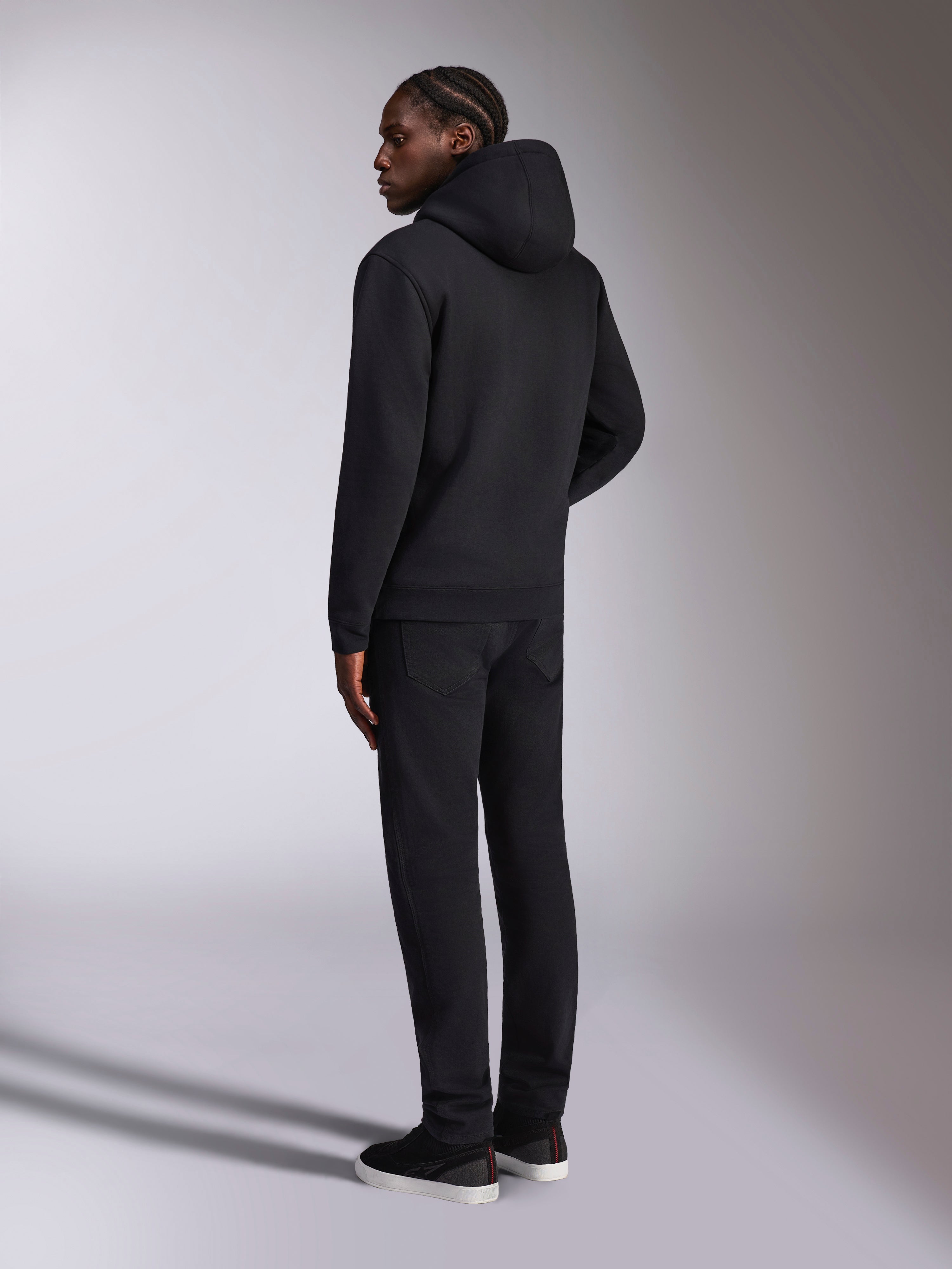 Alpinestars Pulse Hoodie, lässige Streetwear, Schwarz, Rückansicht eines Models in einem einfarbigen schwarzen Kapuzenpullover aus Fleece, minimalistisches Design mit Rippbündchen und Saum