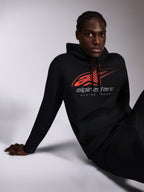 Alpinestars Pulse Kapuzenpullover, Schwarz, lässige Streetwear von einem Model getragen, mit rotem Astars-Logo im Speed-Line-Fade-Design und „alpinestars RACING AHEAD“-Schriftzug auf der Brust, Kapuze mit Kordelzug, lange Ärmel, modernes motorsport-inspiriertes Design