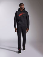Alpinestars Pulse Hoodie, schwarzer lässiger Streetwear-Hoodie, rot-graues Astars-Logo mit Speed-Line-Verlauf auf der Brust, Kapuze mit Kordelzug, Kängurutasche vorne, lange Ärmel, kombiniert mit schwarzer Hose und Sneakern, vom Motorsport inspiriertes Design