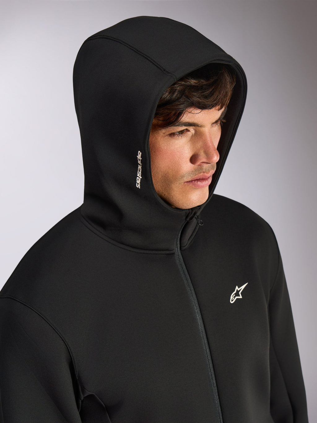Alpinestars Cypher Hoodie, black zip-front hoodie with high neck hood, white Alpinestars word logo on hood and star logo on chest, casual motorsport-inspired streetwear