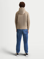 Alpinestars Cypher Hoodie, Sportswear-Fleece-Hoodie für Herren und Damen, Putty Beige, Rückansicht am Modell, Kapuze mit hohem Kragen und Mesh-Futter, Tri-Blend-Performance-Gewebe, motorsport-inspirierte Freizeitkleidung.
