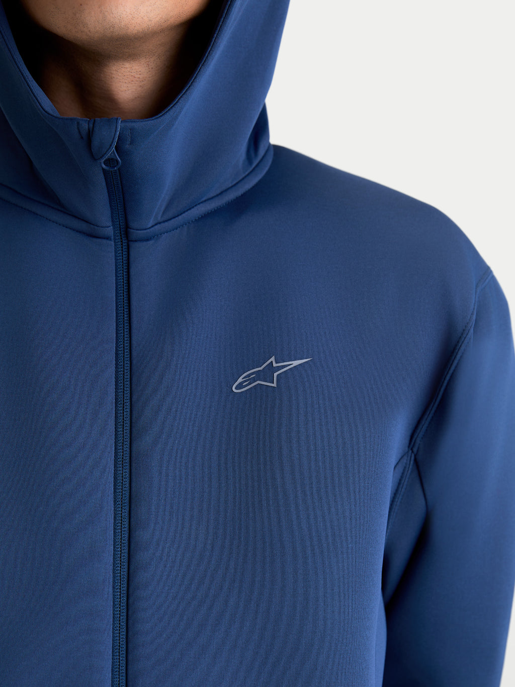 Alpinestars Cypher Hoodie, Sportswear-Hoodie mit Reißverschluss für Herren und Damen, Stahlblau, technisches Tri-Blend-Doppelgewebe-Fleece, mit Kapuze mit hohem Kragen und Astars-Logo, Nahaufnahme am Model.