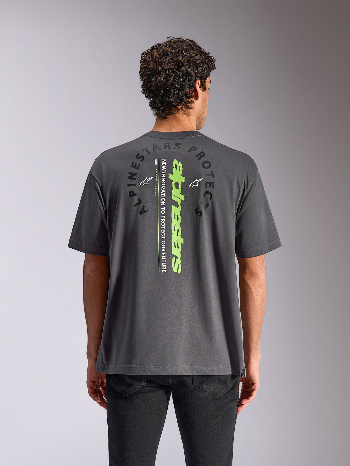 Alpinestars Overhang Oversized CSF Tee, Kurzarm-T-Shirt, Anthrazitgrau, Rückansicht mit vertikaler neongrüner Wortmarke und kreisförmiger Grafik, entspannte Oversized-Passform, lässige Motorsport-Streetwear