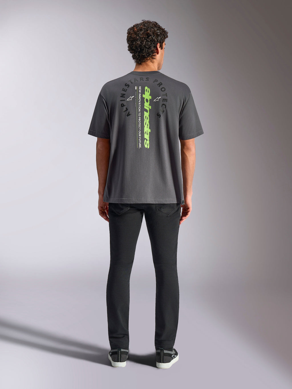 Alpinestars Overhang Oversized CSF Tee, kurzärmeliges T-Shirt, Anthrazitgrau, Rückansicht mit vertikalem neongrünem Alpinestars-Logo und Grafiktext, Oversized-Passform, lässige Motorsport-Streetwear