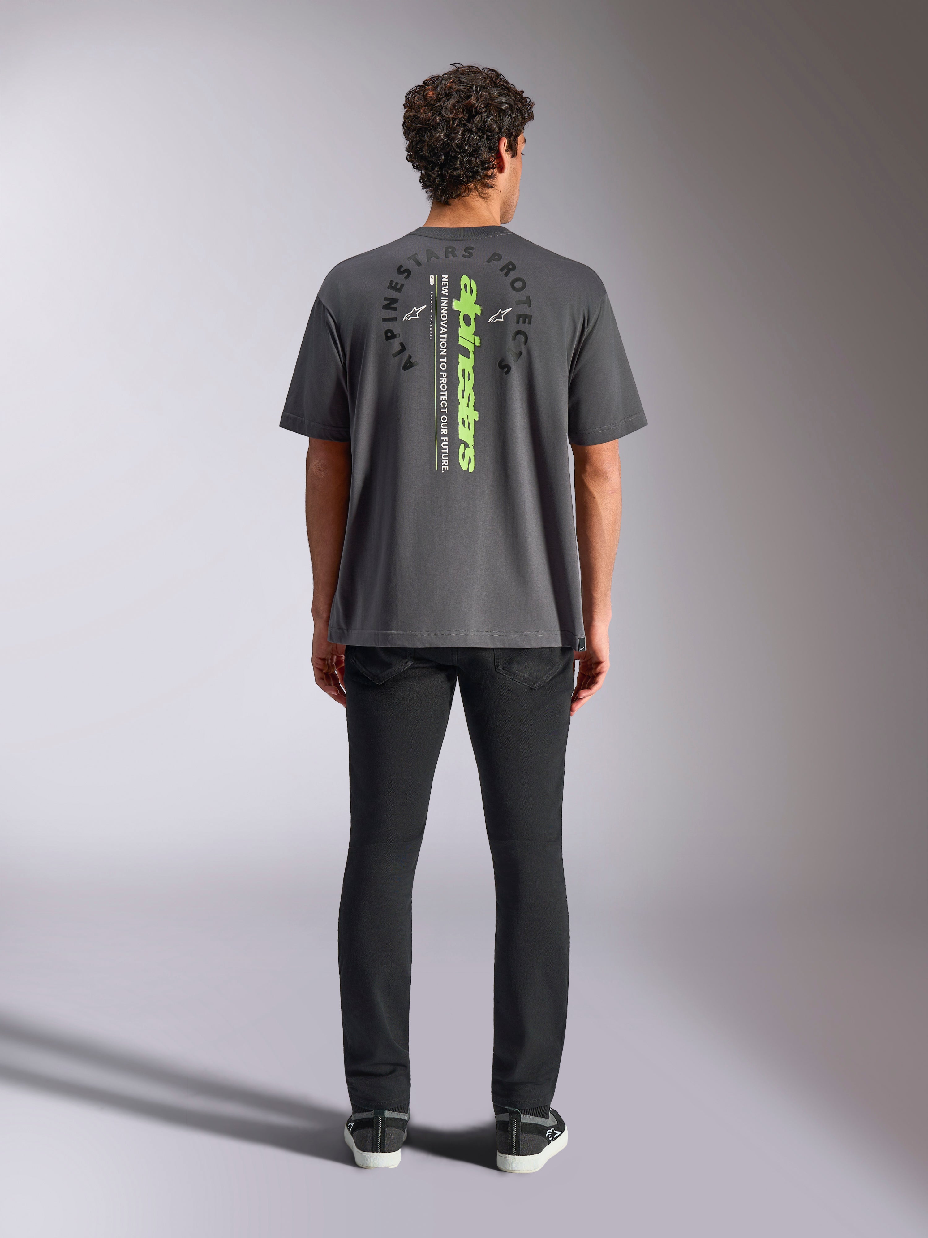Alpinestars Overhang Oversized CSF Tee, kurzärmeliges T-Shirt, Anthrazitgrau, Rückansicht mit vertikalem neongrünem Alpinestars-Logo und Grafiktext, Oversized-Passform, lässige Motorsport-Streetwear