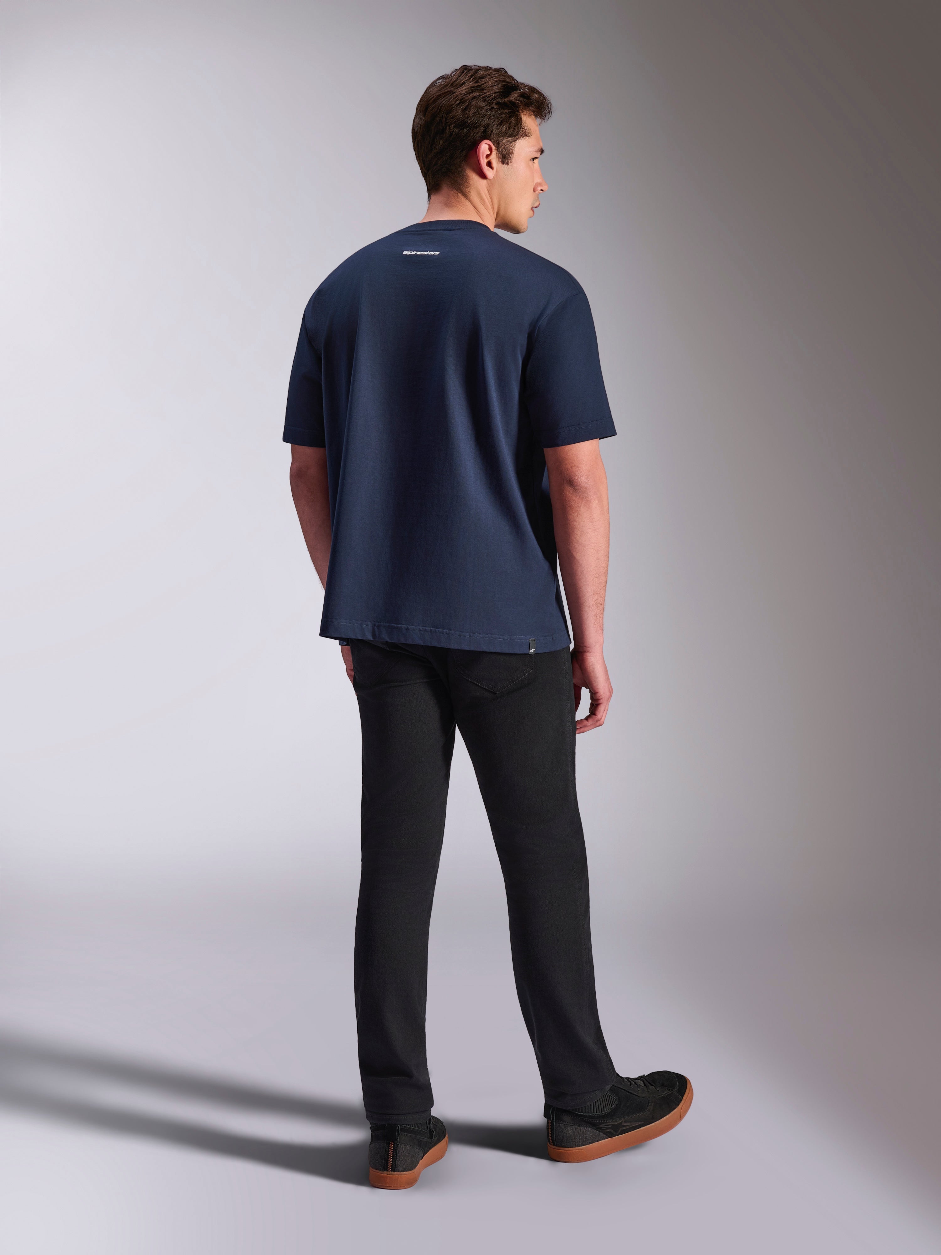 Alpinestars Focused Oversized CSF Tee, Kurzärmeliges T-Shirt, Marineblau, Rückansicht mit kleinem weißem Alpinestars-Wortlogo am Nacken, getragen mit schwarzer Hose, lässige Lifestyle-Bekleidung
