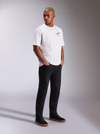 Alpinestars Wild Oversized CSF Tee, kurzärmeliges T-Shirt, Weiß, mit kleinem mehrfarbigem Astars-Logo auf der Brust, getragen von einem Model mit schwarzer Hose und schwarzen Sneakern, lässige, vom Motorsport inspirierte Streetwear