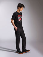 Alpinestars Noka CSF Tee, kurzärmeliges T-Shirt, Schwarz, Front Astars Logo mit rot-weißem MX-Verlauf, getragen mit schwarzer Cargohose und Sneakern, lässige, vom Motorsport inspirierte Streetwear