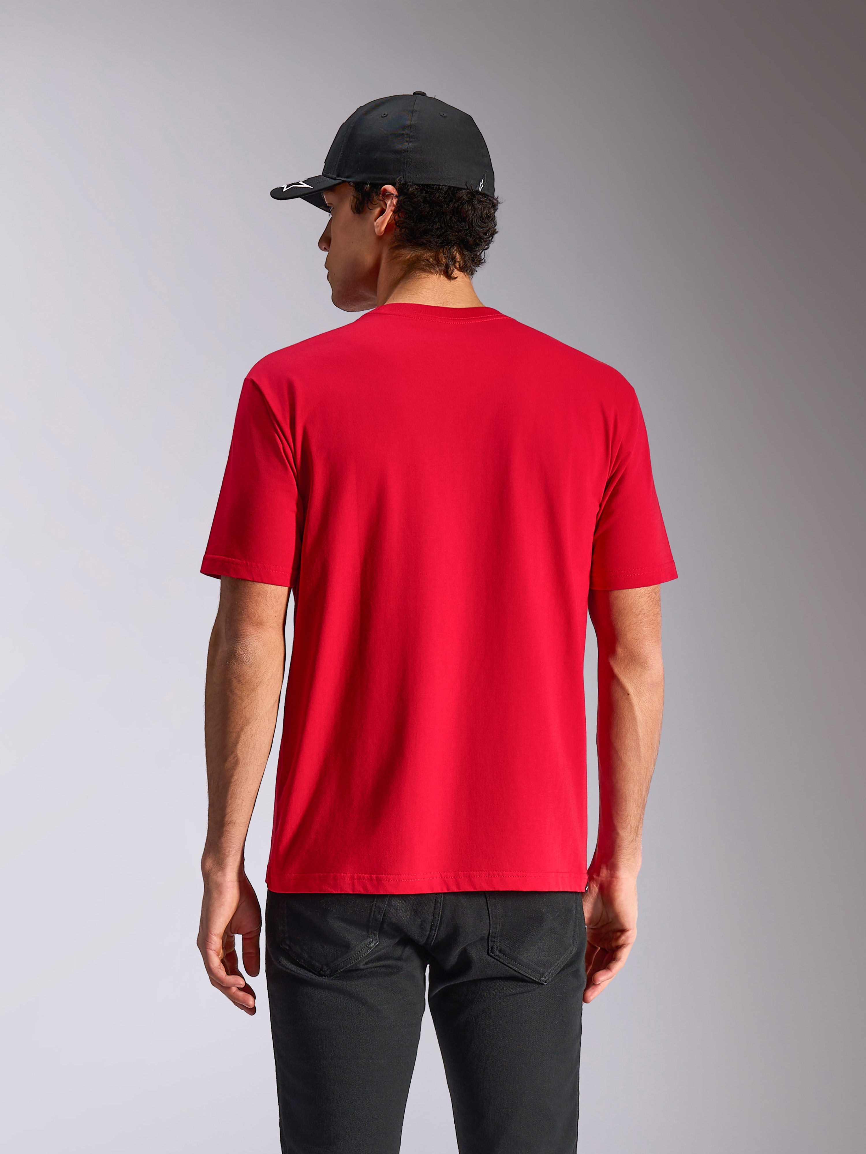 Alpinestars Noka CSF Tee, Kurzarm-T-Shirt, Rot, Rückansicht am Model, lässige Motorsport-Streetwear, kombiniert mit schwarzer Kappe und dunkler Hose
