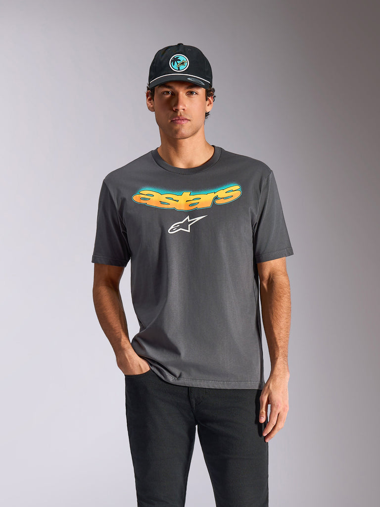 Alpinestars Ellipsoid CSF Tee, Kurzarm-T-Shirt, Anthrazitgrau, gebogener „astars“-Schriftzug mit orange-blauem Farbverlauf und weißem Logo, getragen von einem Model mit schwarzer Kappe und Hose, lässige Motorsport-Streetwear