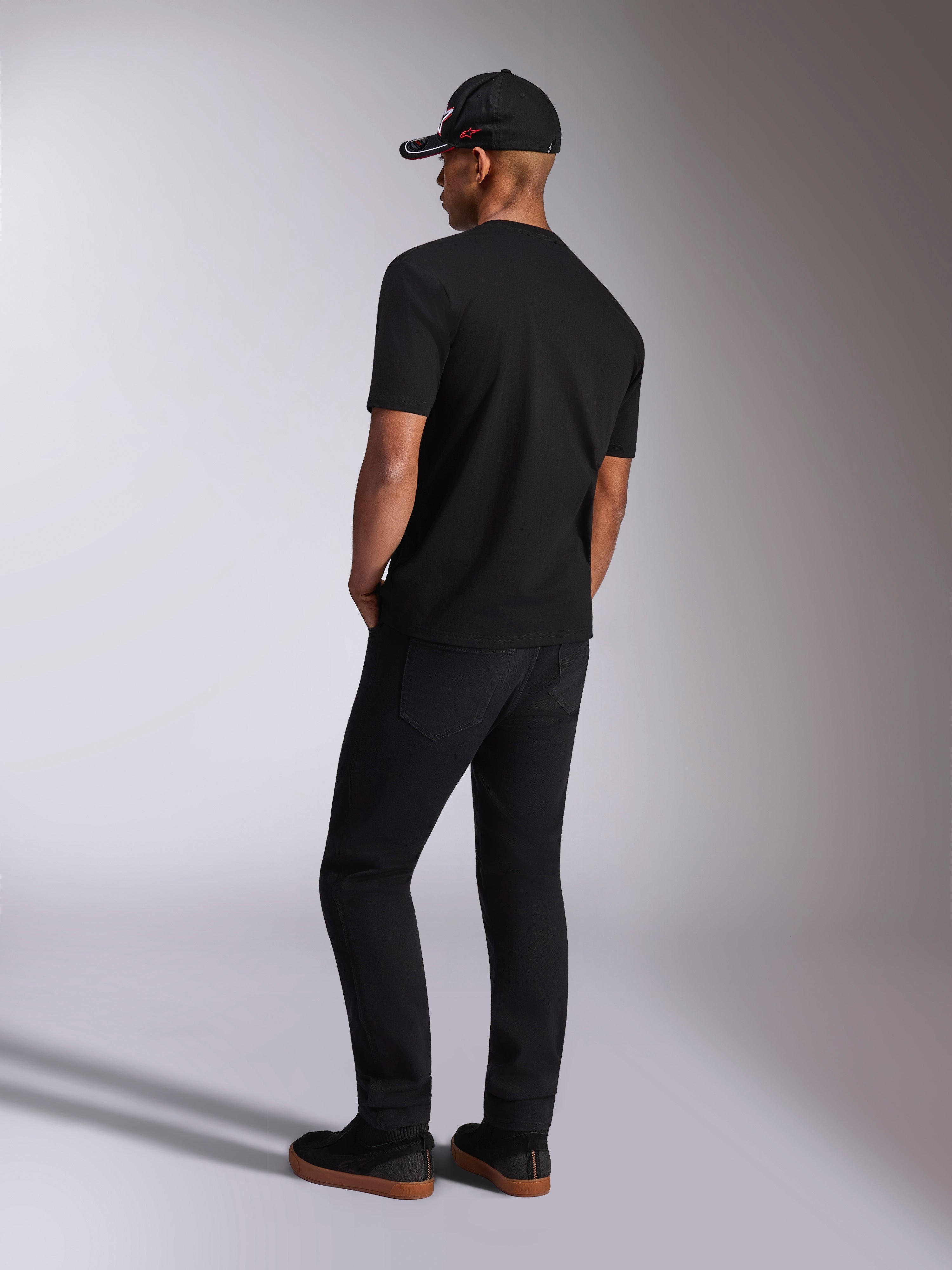 Alpinestars Plate CSF Tee, Kurzarm-T-Shirt, Schwarz, Rückansicht am Model mit schwarzer Hose und Baseballkappe, lässige Motorsport-Streetwear