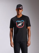 Alpinestars Plate CSF Tee, Kurzarm-T-Shirt, Schwarz, mit MX-Plattengrafik auf der Vorderseite, weißem Logo sowie roten und blauen Akzenten, getragen von einem Model mit passender schwarzer Kappe, lässige Motorsport-Streetwear