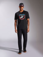 Alpinestars Plate CSF T-Shirt, Kurzarm, Schwarz, MX-Plattengrafik auf der Vorderseite mit weißem Astars-Logo und blauen sowie roten Akzenten, getragen von einem Model mit passender schwarzer Kappe und Hose, lässige Motorsport-Sportbekleidung